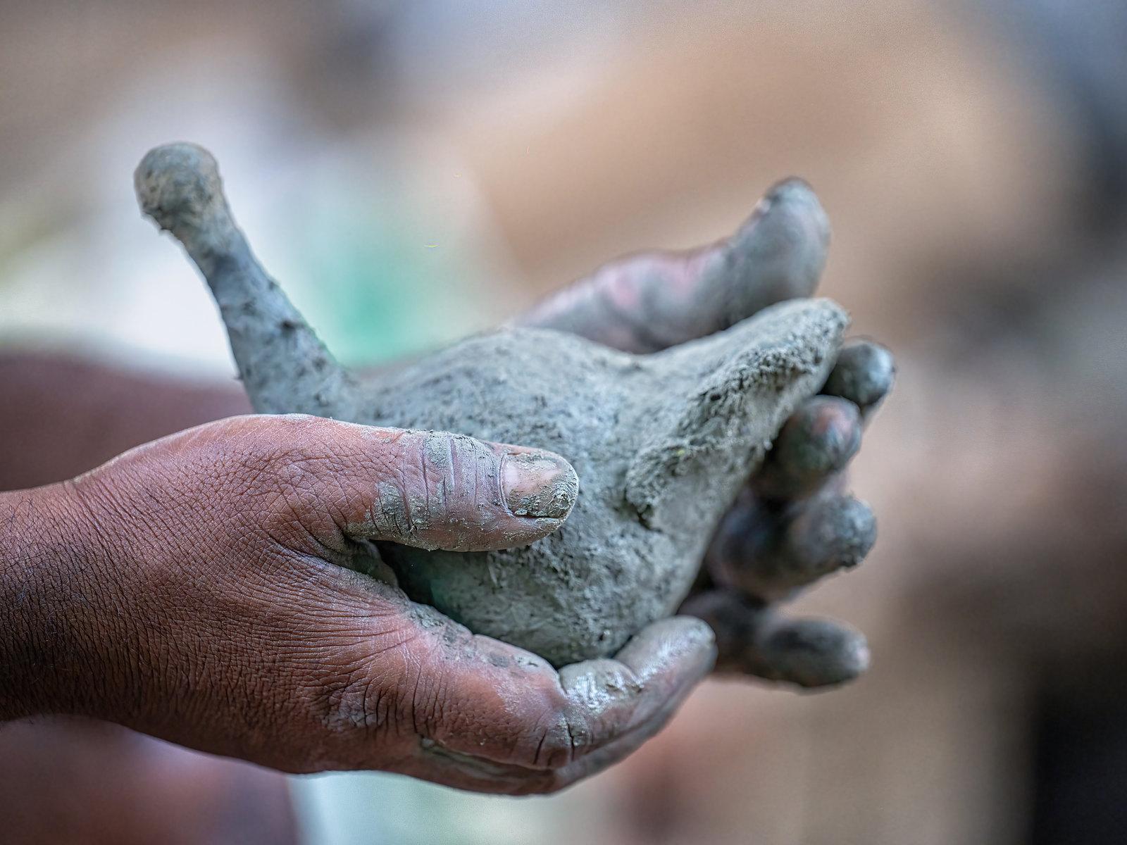 Hands cradling a wet clay core, the animal form still soft and unfired.