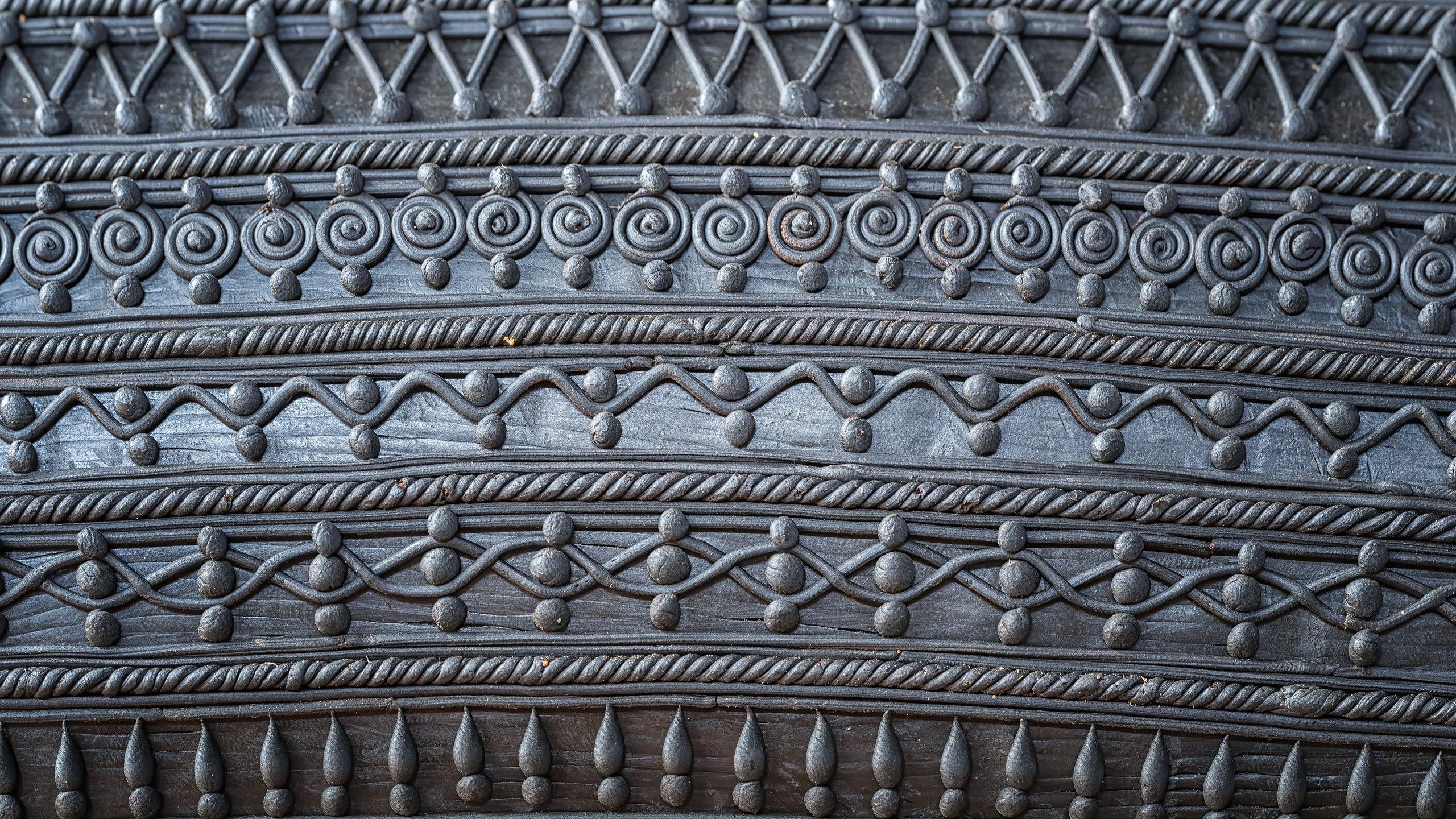 A wound wax surface at close range, in rows of spirals, chevrons and beading, each line laid separately.